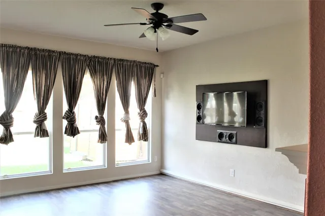 a view of an empty room with a window and wooden floor