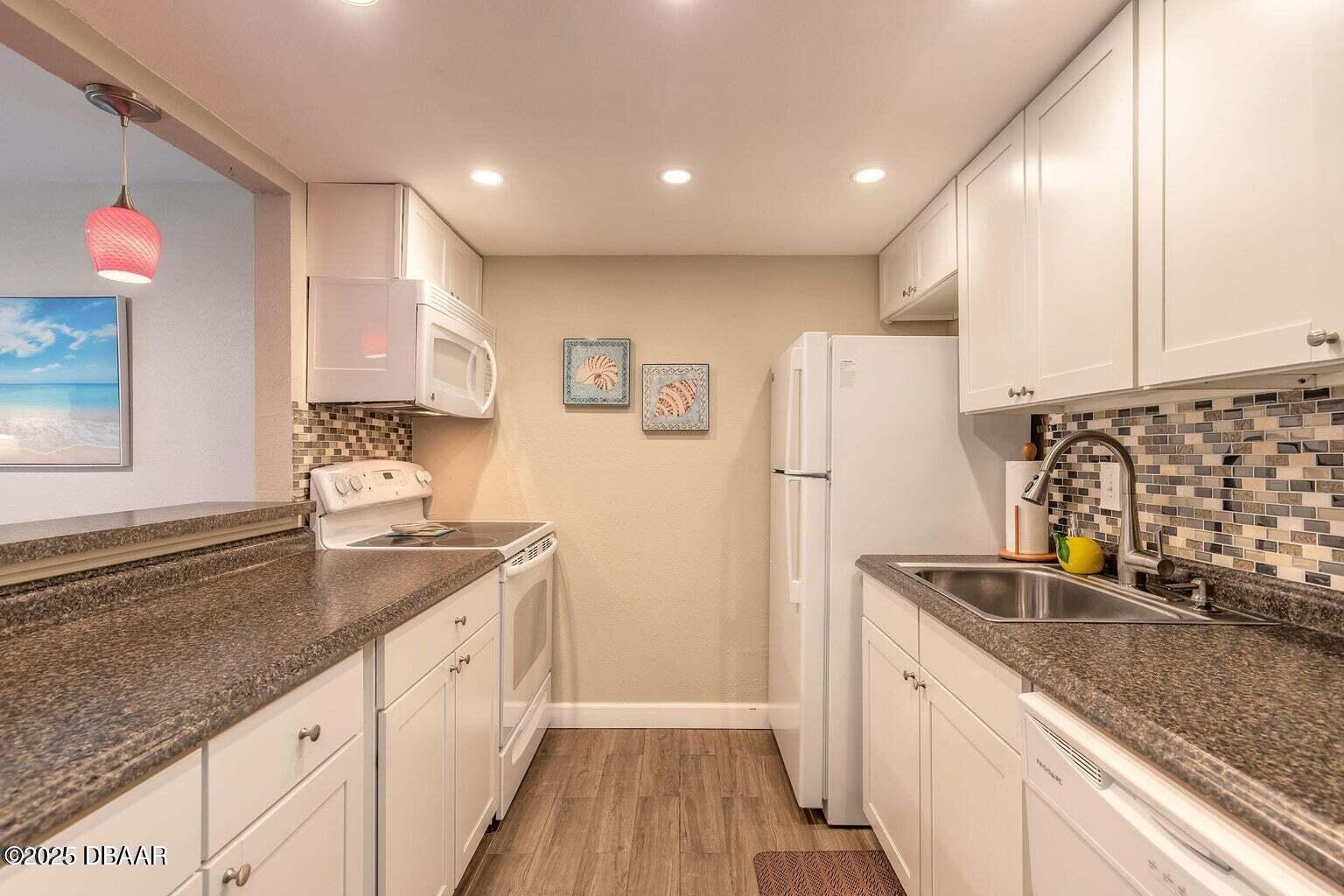 2750 Ocean Shore Boulevard, Unit 19 Ormond Beach, FL 32176 - Photo 8 of 23 a kitchen with granite countertop a sink stove and refrigerator