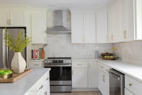 a kitchen with stainless steel appliances a stove a sink and a white cabinets