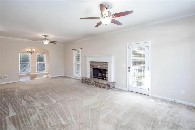 a view of a livingroom with a chandelier fan and kitchen view