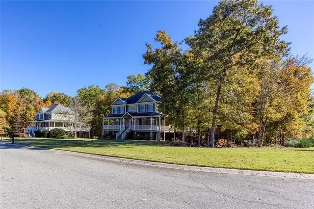 a view of a house with a big yard and large trees
