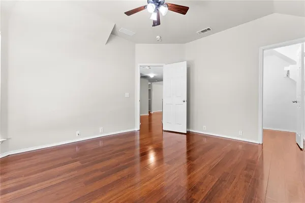 an empty room with wooden floor ceiling fan and window
