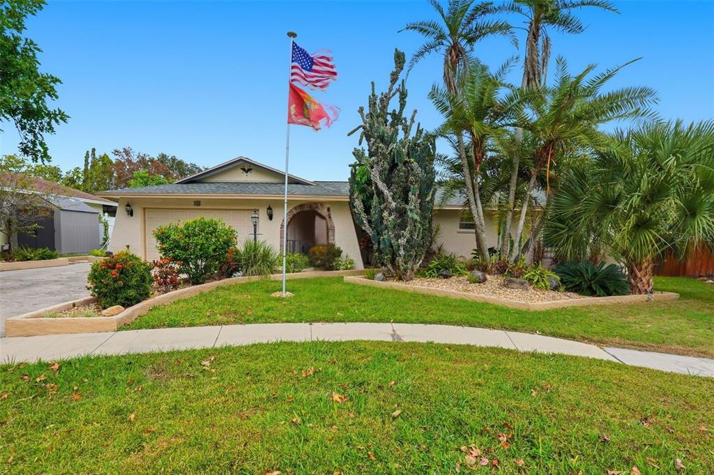 a front view of a house with a yard and palm trees
