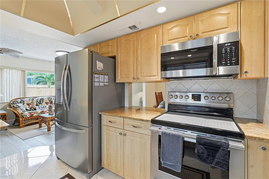 2370 Robyn Court Dunedin, FL 34698 - Photo 9 of 29 a kitchen with stainless steel appliances granite countertop a stove and a refrigerator