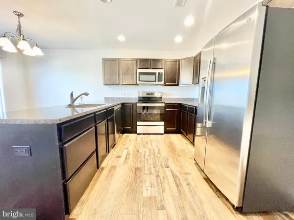 a kitchen with stainless steel appliances granite countertop a refrigerator a stove and a sink