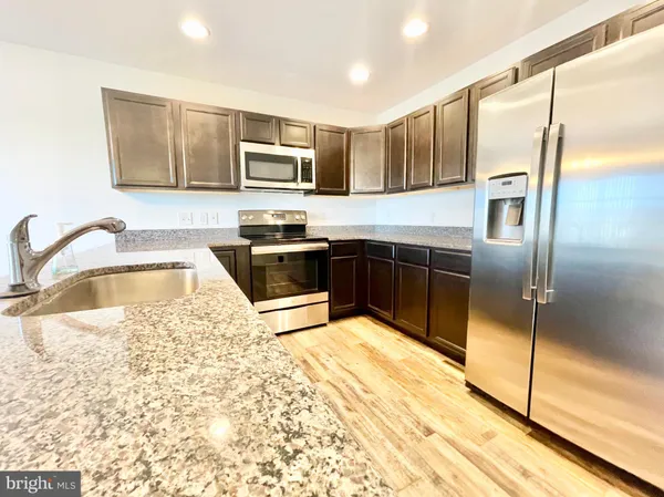 a kitchen with stainless steel appliances granite countertop a sink refrigerator and microwave
