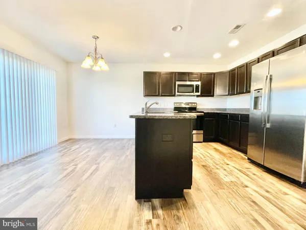 a kitchen with kitchen island stainless steel appliances a sink cabinets and wooden floor