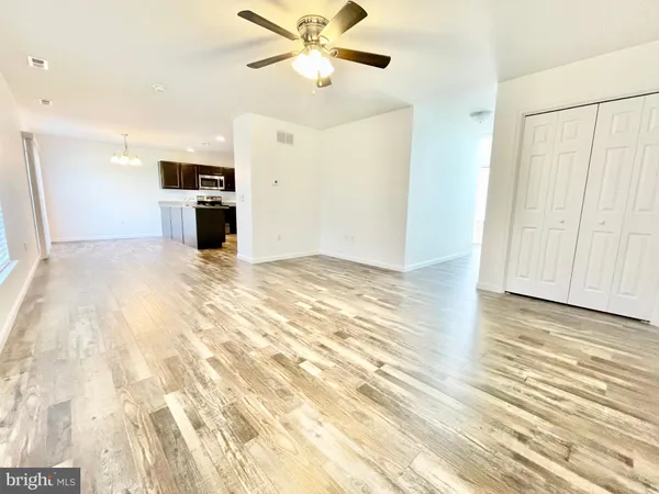 an empty room with kitchen appliances and a ceiling fan