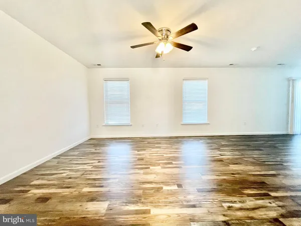 a view of a room with wooden floor and ceiling fan