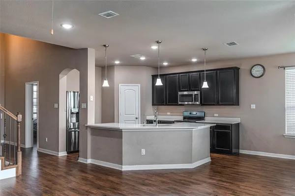 a open kitchen with stainless steel appliances granite countertop a sink dishwasher a stove and a refrigerator with wooden floor