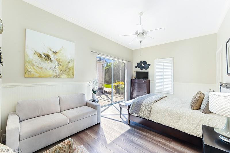 11234 5 Oaks Lane Naples, FL 34120 - Photo 16 of 34 a bedroom with a bed a couch and a chandelier