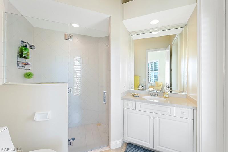11234 5 Oaks Lane Naples, FL 34120 - Photo 17 of 34 a bathroom with a sink a mirror a shower and a bathtub