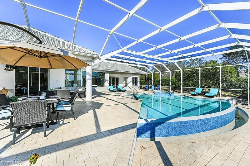 11234 5 Oaks Lane Naples, FL 34120 - Photo 23 of 34 a view of a patio with a table and chairs under an umbrella