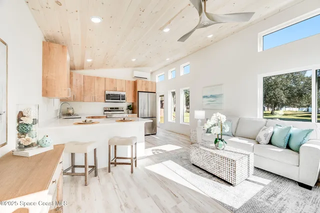 a living room with stainless steel appliances kitchen island granite countertop furniture a rug kitchen view and a chandelier