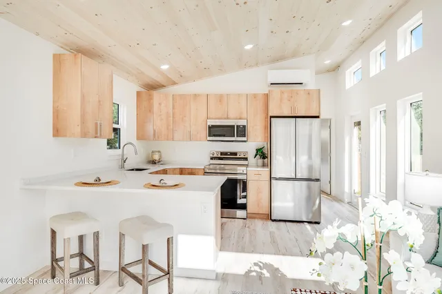 a kitchen with stainless steel appliances granite countertop a refrigerator a stove a sink a dining table and chairs with wooden floor