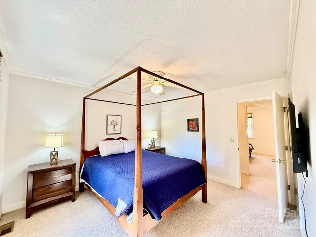 a bedroom with a bed and a flat tv screen on the dresser