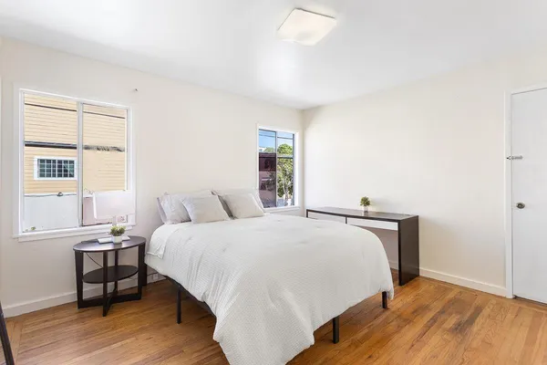 a bedroom with a bed a table and windows