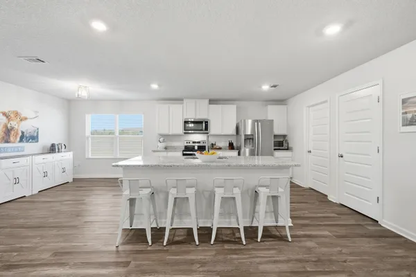 a kitchen with stainless steel appliances a refrigerator a stove top oven and white cabinets