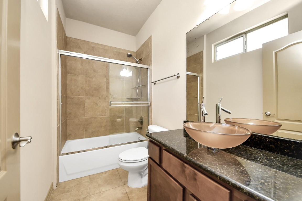 5711 Kiam Street Houston, TX 77007 - Photo 16 of 30 a bathroom with a granite countertop sink toilet a mirror and shower