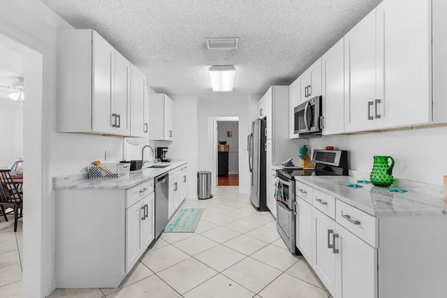 a kitchen with stainless steel appliances granite countertop white cabinets a stove top oven a sink and dishwasher