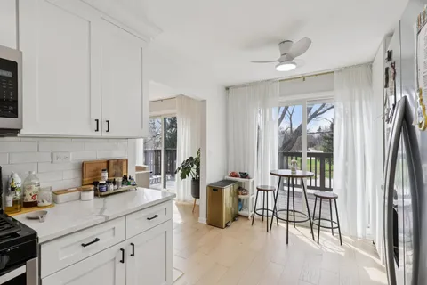 a kitchen with stainless steel appliances granite countertop a refrigerator a sink and white cabinets