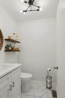 a bathroom with a toilet a sink and wooden floor
