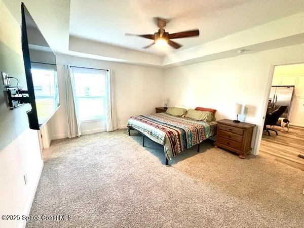 a spacious bedroom with a bed a couch and a chandelier