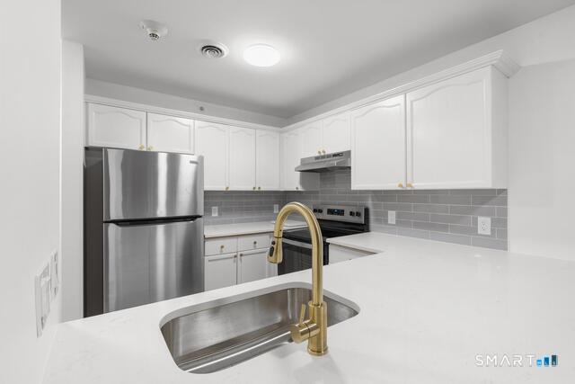 468 Main Street, Unit 318 East Lyme, CT 06357 - Photo 22 of 33 a kitchen with a refrigerator a stove a microwave and white cabinets
