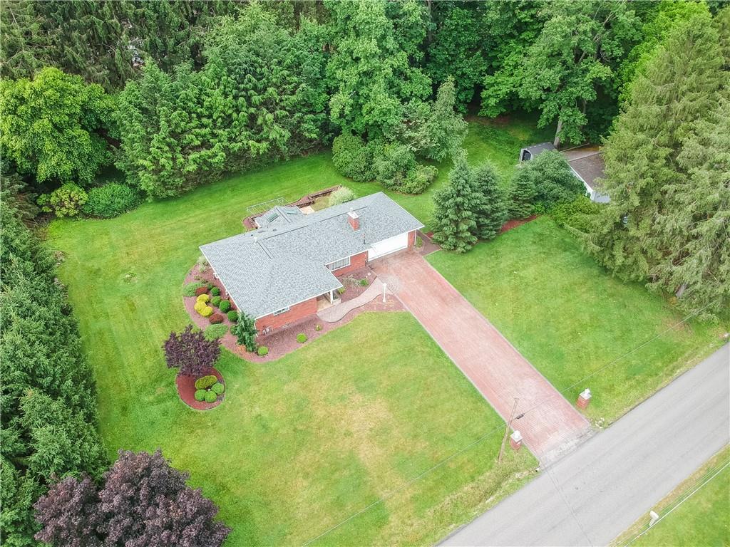 119 Beacon Road Renfrew, PA 16053 - Photo 3 of 49 Aerial view showcasing the home's attractive setting, mature landscaping, and expansive yard surrounded by established trees. The expansive homesite features a detached garage perfect for yard toys and tools.
