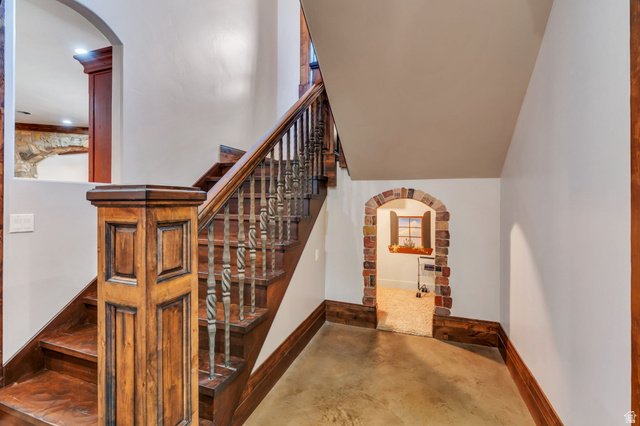 811 South High Ridge Drive Alpine, UT 84004 - Photo 42 of 98 Stairway featuring arched walkways, concrete flooring, and a high ceiling