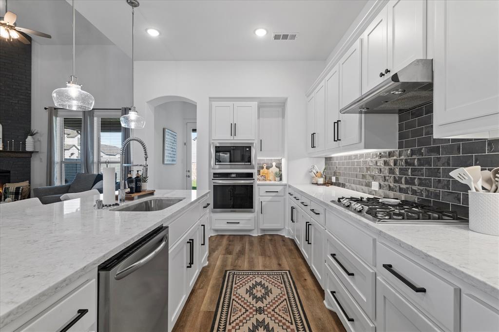 1332 Thompson Road Argyle, TX 76226 - Photo 11 of 36 Kitchen featuring light stone countertops, stainless steel appliances, white cabinets, ceiling fan, and backsplash