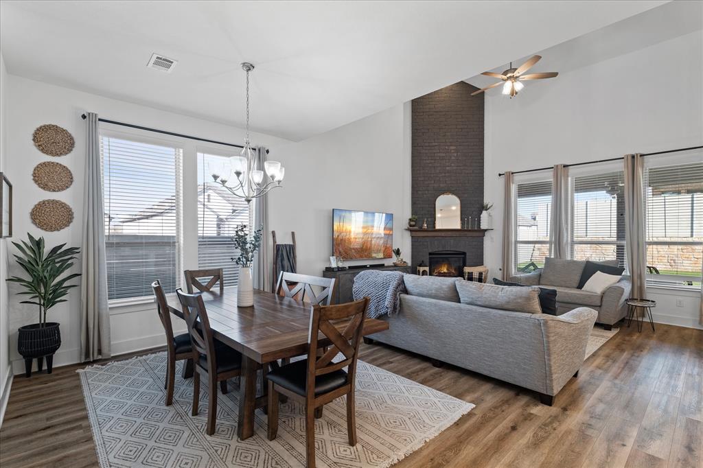 1332 Thompson Road Argyle, TX 76226 - Photo 4 of 36 Dining room featuring lofted ceiling, a brick fireplace, dark wood-type flooring, a ceiling fan, and a chandelier