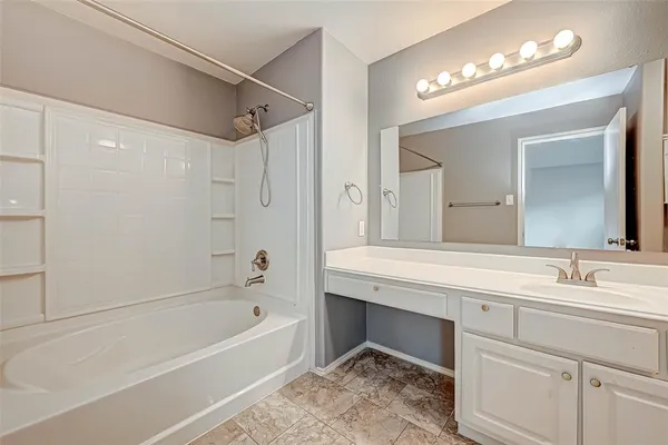 a bathroom with a tub a sink and a mirror