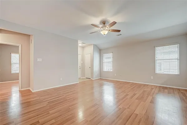 a view of an empty room with wooden floor and a window