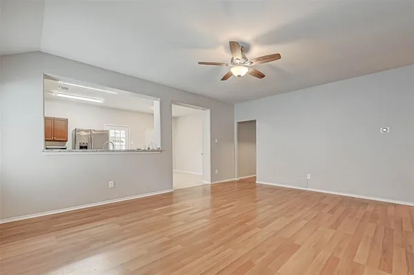 a view of an empty room with wooden floor and a ceiling fan