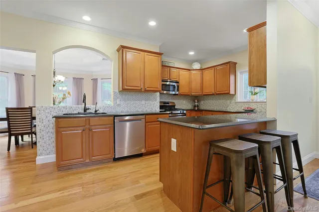 a kitchen with stainless steel appliances granite countertop a sink a stove a counter space and cabinets