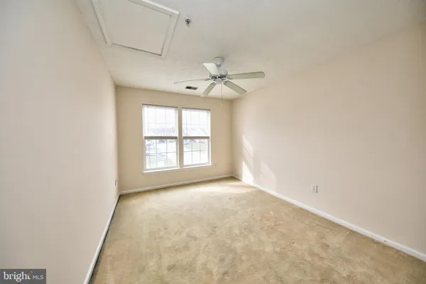 an empty room with a ceiling fan and window
