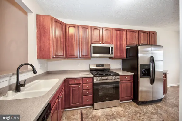 a kitchen with stainless steel appliances granite countertop a stove top oven a sink and dishwasher