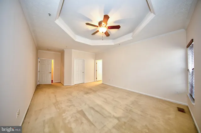 a view of an empty room with a ceiling fan and window