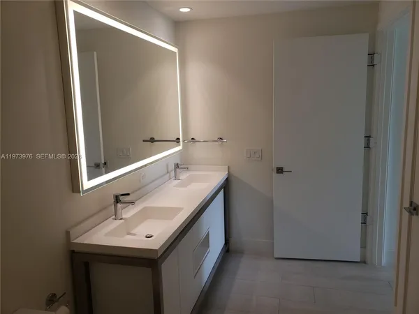 an empty room and a bathroom with a sink