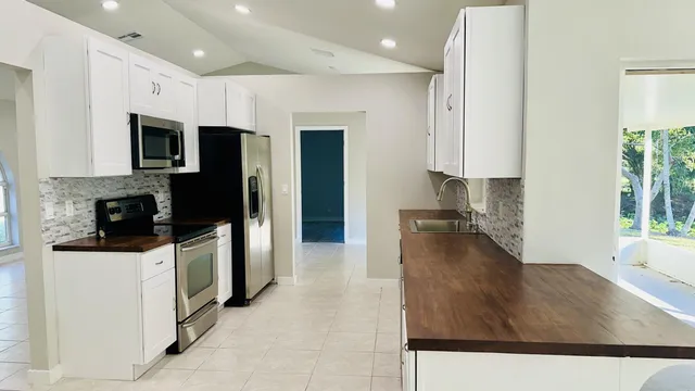 a kitchen with stainless steel appliances kitchen island granite countertop a refrigerator a stove and a sink with wooden floor