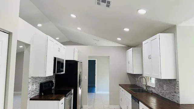 a kitchen with stainless steel appliances granite countertop a refrigerator a stove and a sink