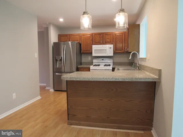 a kitchen with kitchen island granite countertop wooden cabinets and a refrigerator