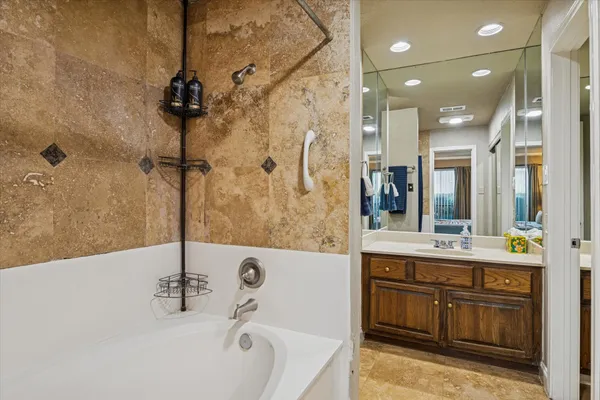 a bathroom with a tub sink and mirror