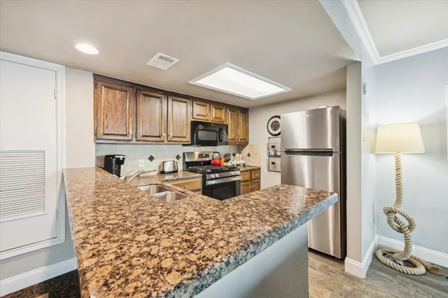 a living room with stainless steel appliances granite countertop a couch and a large window with the outer view