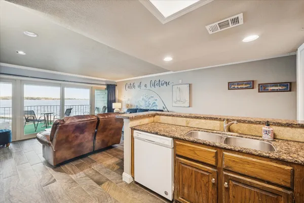 a living room with stainless steel appliances granite countertop a couch and a large window with the outer view