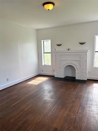 an empty room with wooden floor and a fireplace