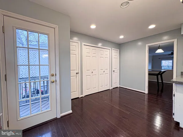 an empty room with wooden floor ceiling fan and windows