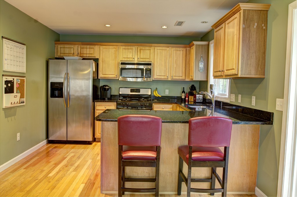 262 Littleton Road, Unit 22 Chelmsford, MA 01824 - Photo 4 of 30 a kitchen with stainless steel appliances granite countertop a refrigerator a stove top oven a sink dishwasher and wooden cabinets