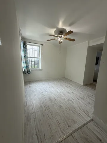 an empty room with wooden floor fan and windows
